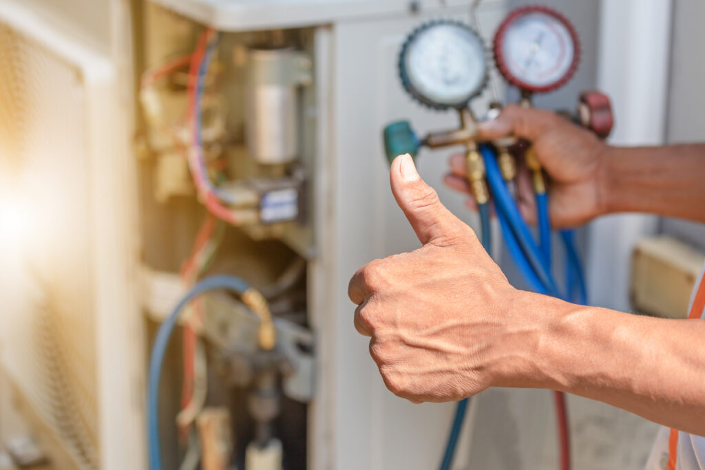 Guy doing thumbs up hand sign while fixing HVAC system